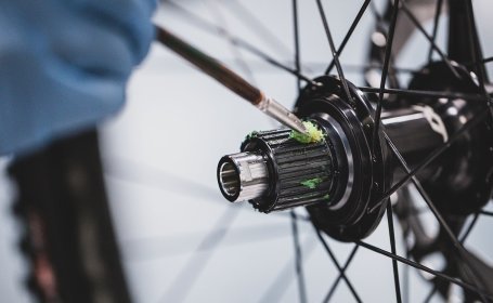 A wheel freehub is being greased before the cassette is mounted.