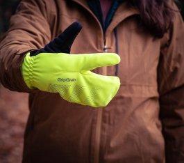 Eine Person hält einen neongelben Lobster-Fahrradhandschuh in die Kamera. Daumen und Zeigefinger sind abgespreizt.