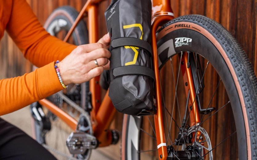 Bikepacking bag mounted on the Adventure fork of an orange OPEN U.P. gravel bike with Zipp wheel.