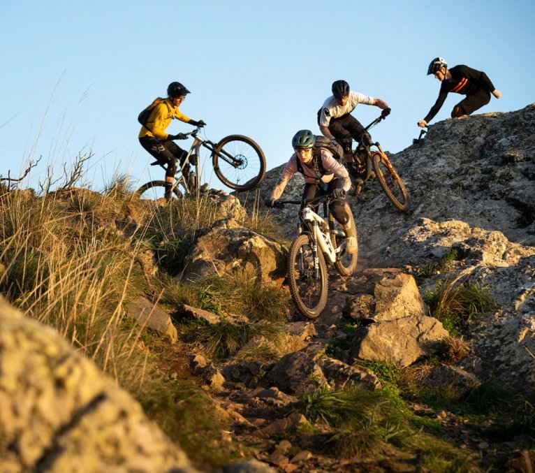 Christoph, Isa y Rainer de bc montando en bicicletas de montaña. El terreno es rocoso.
