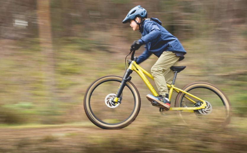 Ein Kind fährt mit dem SUPURB BO24 schnell durch den Wald