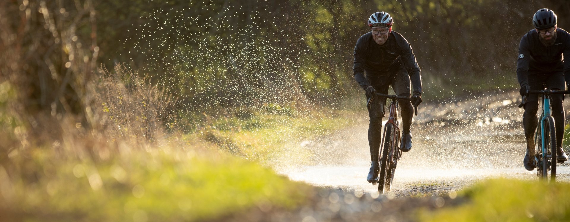 Two gravel bikers ride with verve over a gravel path.