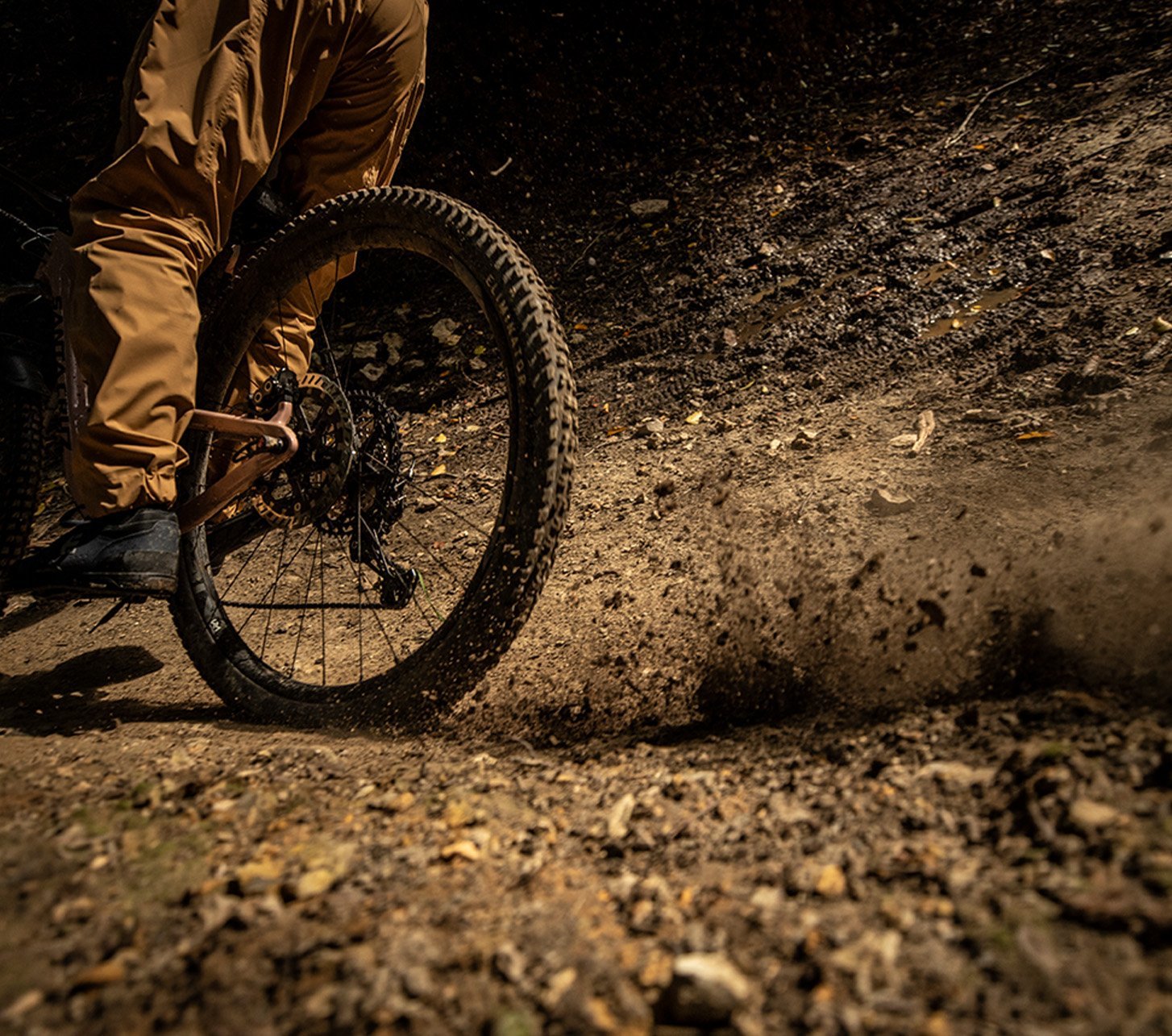 Mountainbiker schleudert mit seinem Hinterreifen Dreck in die Höhe.