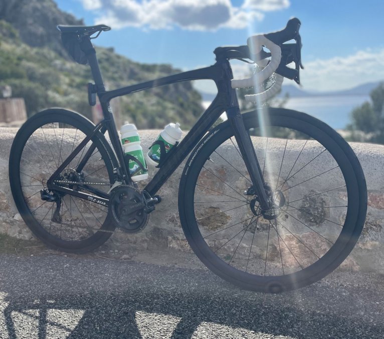 A Specialized Tarmac SL 7 stands leaning against a wall on a coastal road in Mallorca.