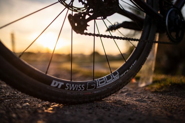 Malerische Detailaufnahme eines DT-Swiss Gravel Laufrads auf festem Schotter im Sonnenuntergang