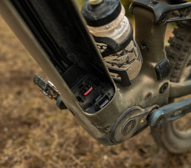 Detailfoto: Blick ins leere Unterrohr eines Turbo Levo 4 E-MTB: Der Akku wurde entnommen, man sieht das Carbongewebe und die Kontakte zum Motorsystem 