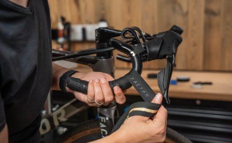Die Mechanikerin wickelt das Lenkerband mit regelmäßigen Abständen.