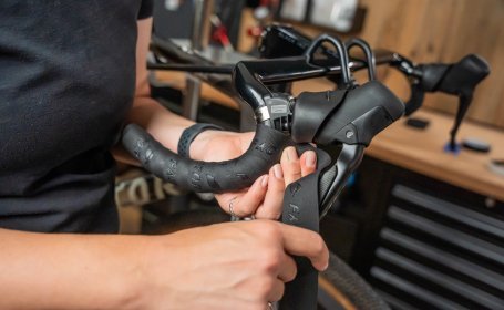 Die Mechanikerin wickelt am Unterlenker so nah wie möglich an den Bremsschaltgriff heran. 