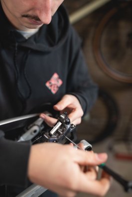 Die Belaghalteschraube wird in einen Scheibenbremssattel eingesetzt. Dieser ist am Heck eines alufarbenen MTB montiert