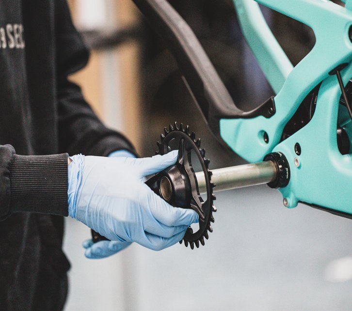 A bc mechanic puts the crank together with the crankshaft into the bottom bracket of a Santa Cruz bike.