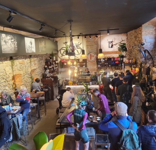 The interior of a busy café in Girona. Bikes and pictures from the cycling world hang on the walls. 