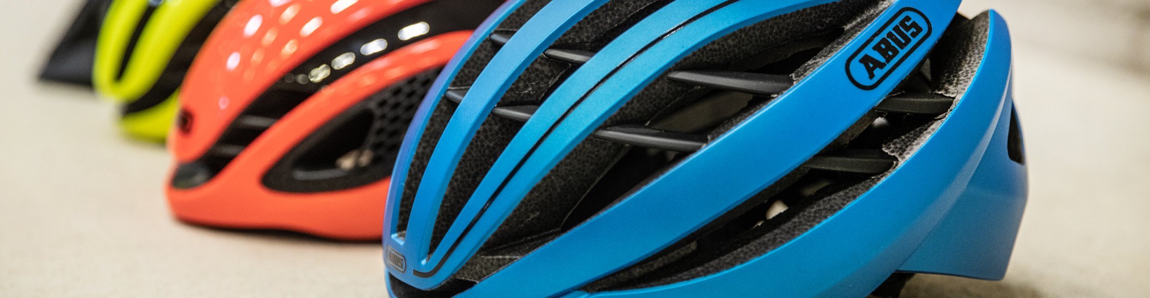 ABUS Fahrradhelme in unterschiedlichen Farben in einer Reihe hintereinander.