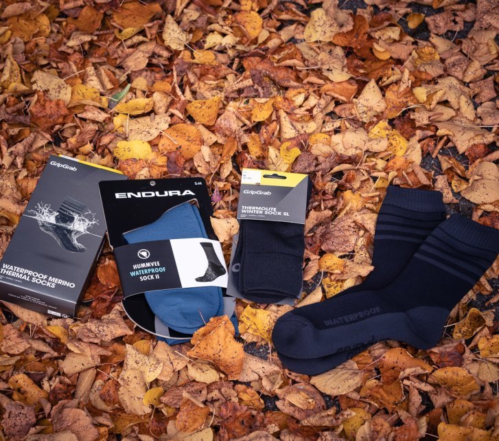 Cuatro pares de calcetines de invierno sobre hojas otoñales rojizas