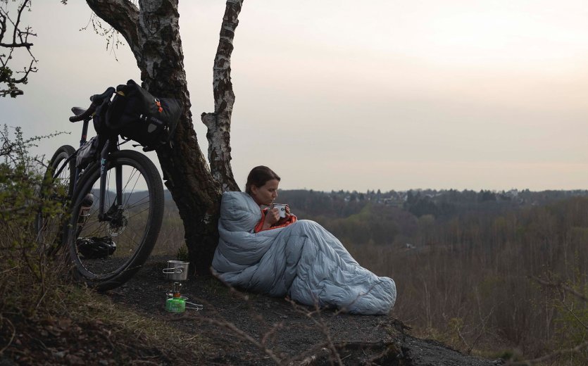 Christian from the bc Service Team packs up his camping mat. In the foreground is his tent, in the background is his bicycle.