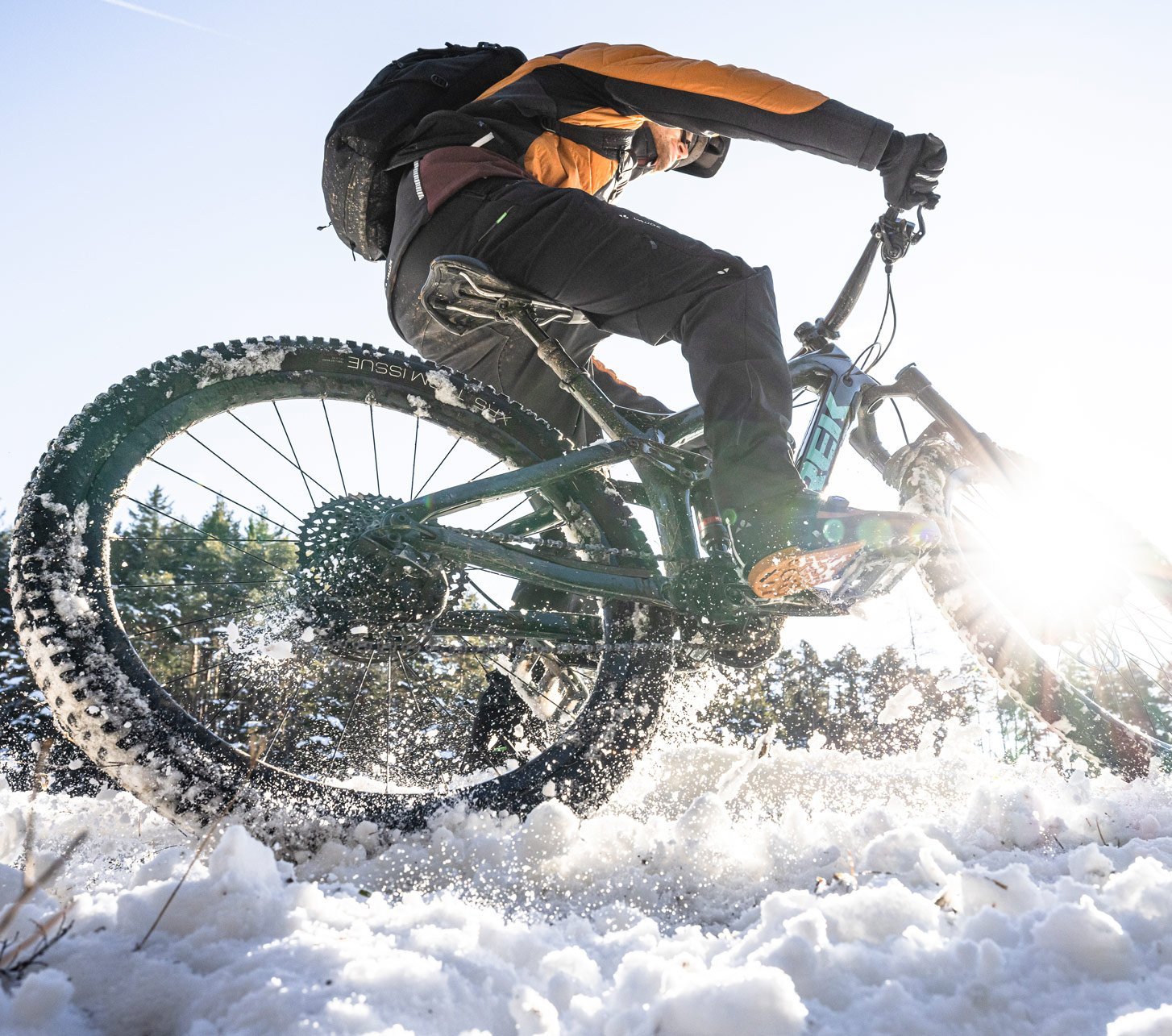 Actionbild von einem mit MTB Hose von Vaude bekleideten Mountainbiker der durch den Schnee fährt.