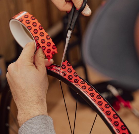 Main coupant le fond de jante avec des ciseaux en formant une extrémité arrondie.