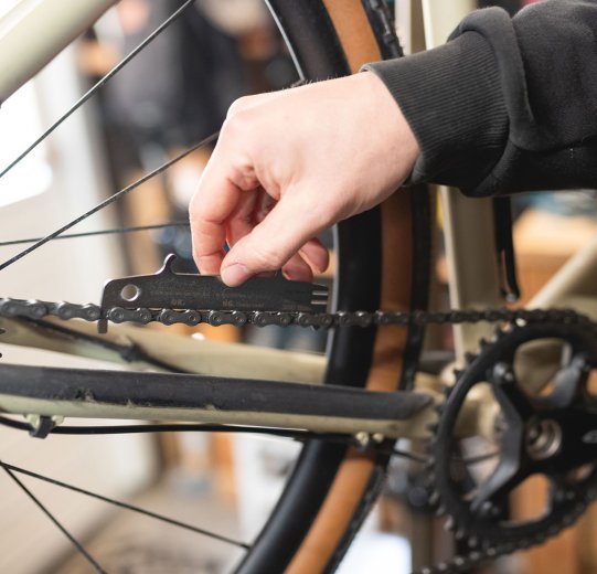 bc Mechaniker Pascal prüft die Kettenlängung mit einer Kettenverschleißlehre. 