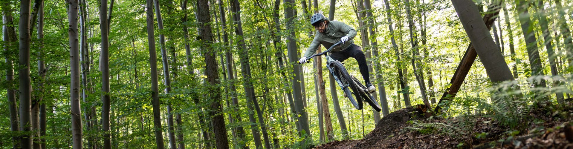 Berno springt mit dem Specialized Turbo Levo R von einem kleinen Kicker im Wald ab.