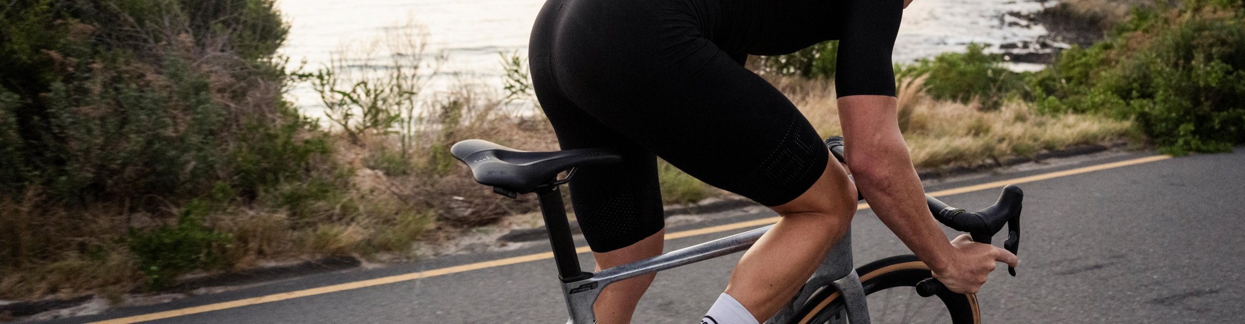 Rennradfahrer mit SQlab Sattel auf einer Küstenstraße – ergonomisches Fahrradzubehör für Performance und Komfort