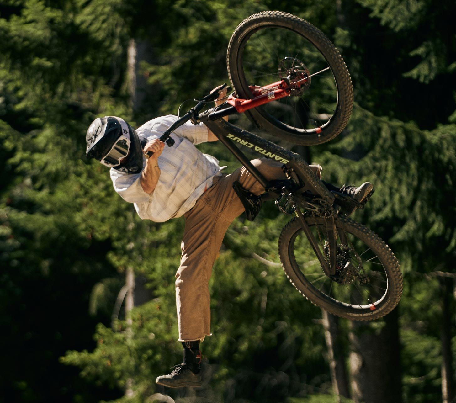 Vététiste en saut avec un Santa Cruz Nomad sur un trail de bike park en forêt.