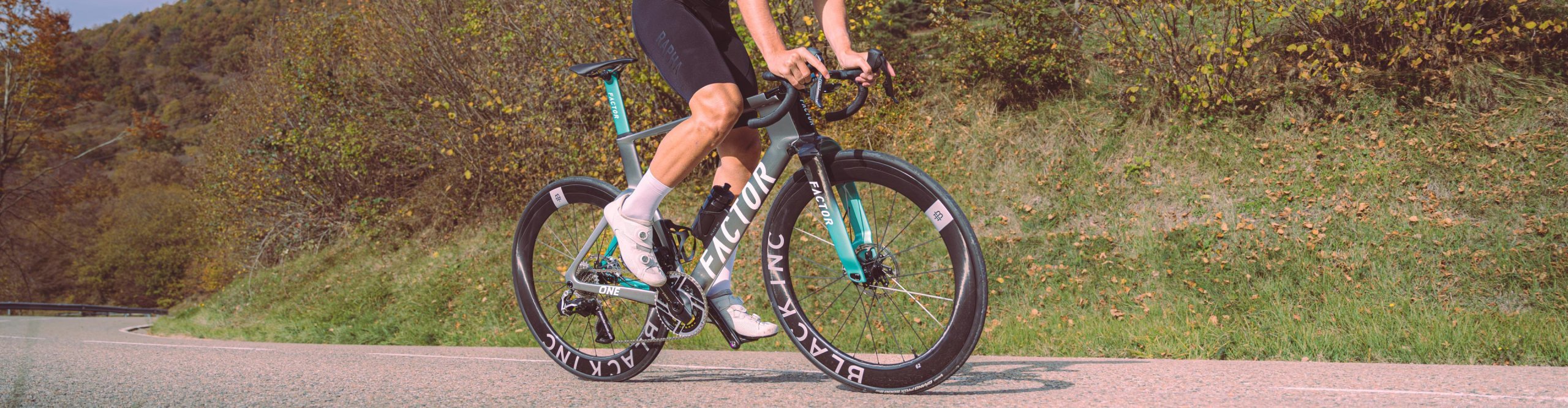 Ein Radfahrer auf dem Factor One Aero-Bike und Black Inc Laufrädern im Wiegetritt.