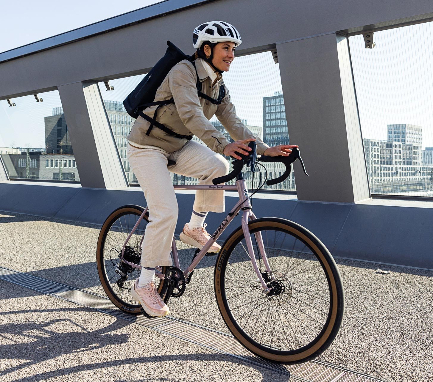 Cycliste avec sac à dos Ortlieb et casque roulant sur une piste cyclable dans une ville moderne
