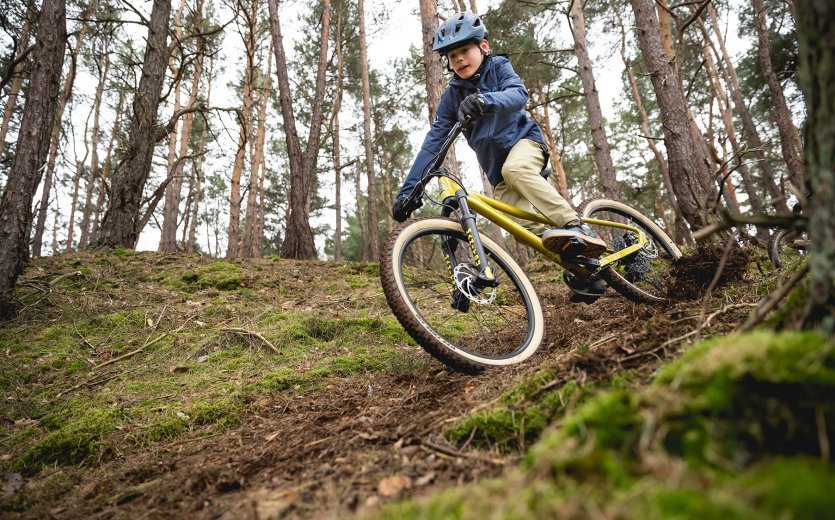 Ein Kind fährt mit dem SUPURB BO24 einen Trail im Wald