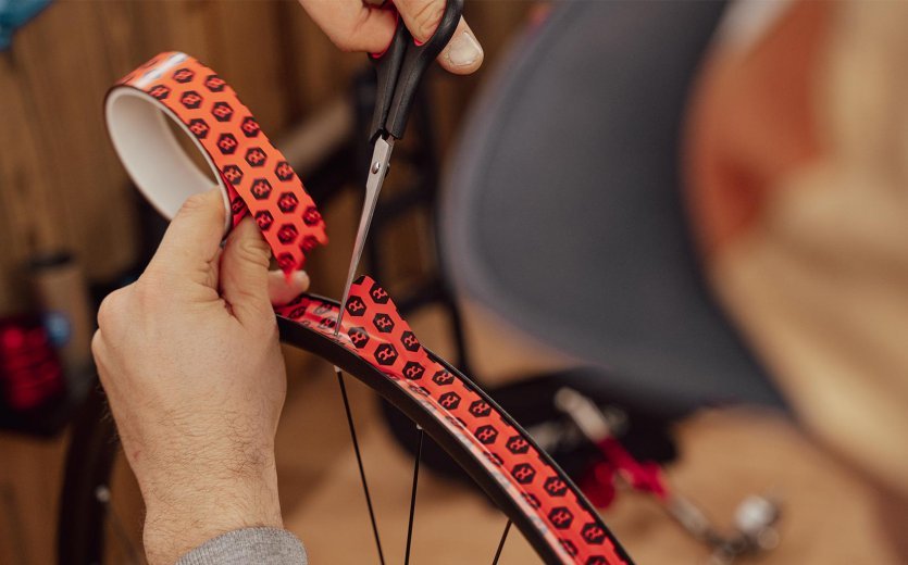 Main coupant le fond de jante avec des ciseaux en formant une extrémité arrondie.