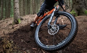 Christian from bc Product Management rides a Yeti MTB downhill along a forest path. The focus of the picture is on the front wheel and tyre of his bike. The tyre is the Butcher from Specialized.