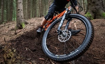 Christian, de gestión de productos de bc, en una MTB Yeti bajando por un camino forestal. El foco de la imagen está en la rueda delantera y en la cubierta de su bicicleta. La cubierta es la Butcher de Specialized.