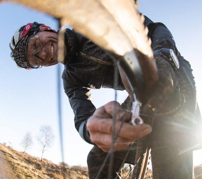 Ein Biker pumpt nach einer Panne Luft in den Schlauch seines Laufrads.