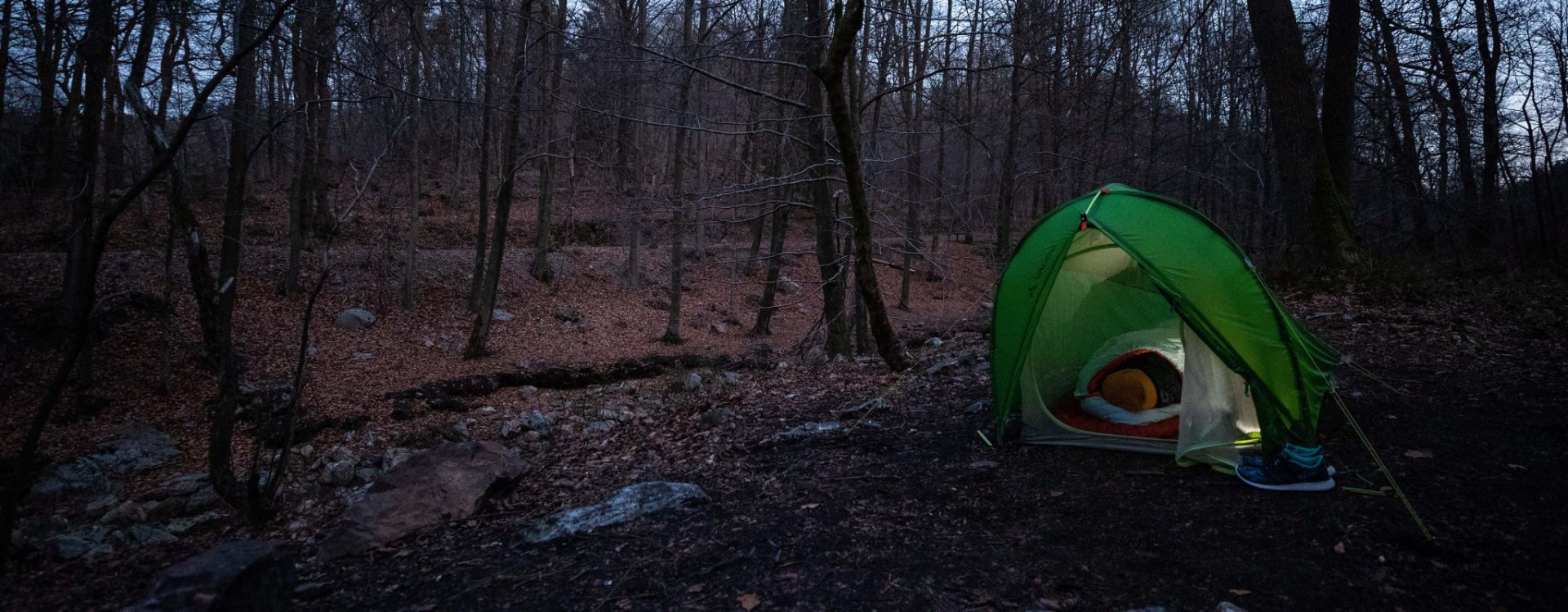 Svenja aus dem bc Produkt Management liegt warm eingepackt in ihrem Deuter Schlafsack in einem VAUDE Zelt.