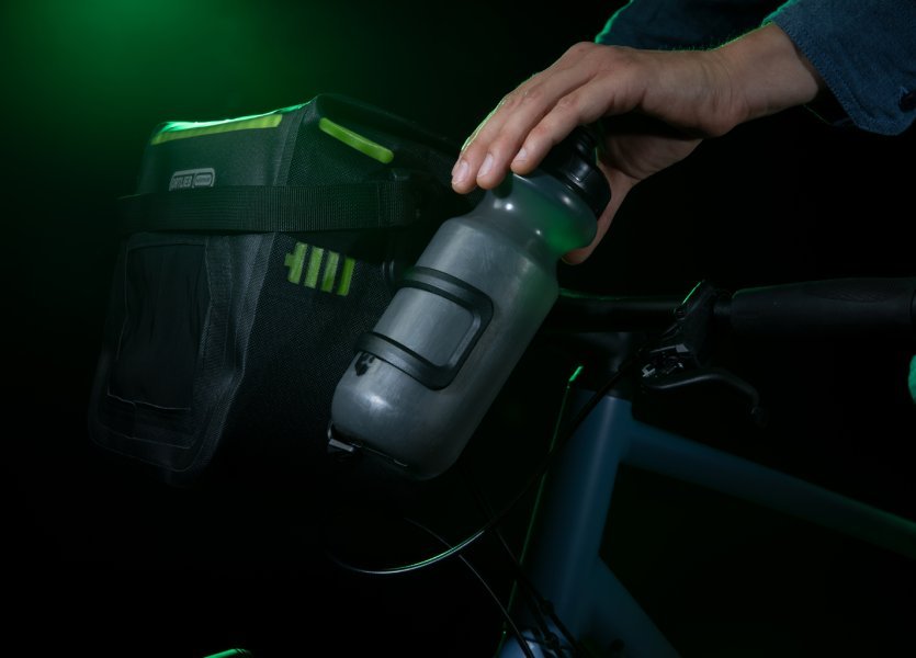 Eine Hand holt die Wasserflasche aus der Seitentasche der ORTLIEB Lenkertasche heraus.