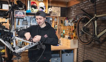 bc Mechaniker Pascal prüft die Hinterradbremse eines RAAW Mountainbikes in einer Hobby-Werkstatt.