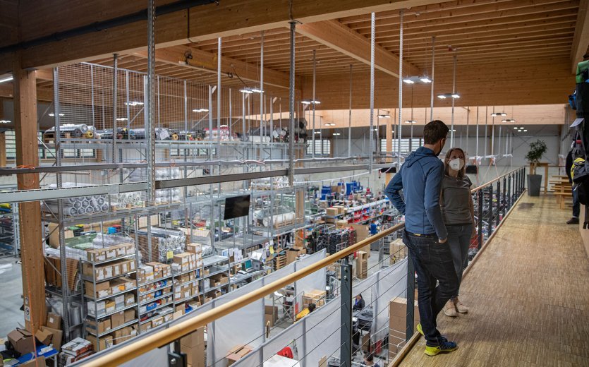 bc-Brandmanagerin Svenja und Vaude-Produktmanager Markus stehen auf einer Galerie über einer Fertigungshalle.