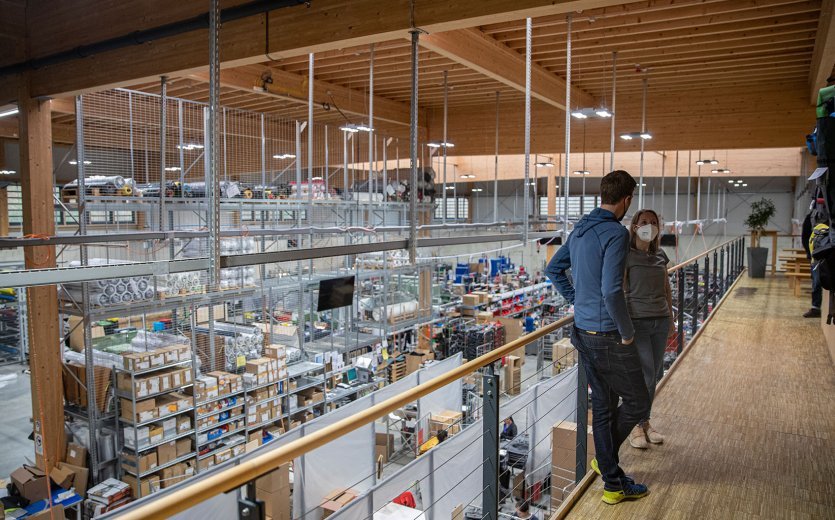 bc-Brandmanagerin Svenja und Vaude-Produktmanager Markus stehen auf einer Galerie über einer Fertigungshalle.