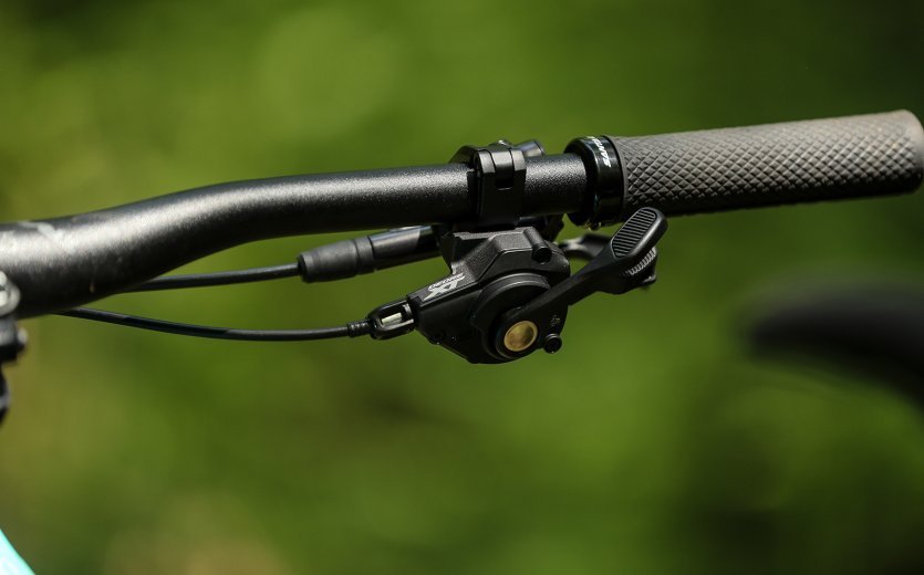 An einem Mountainbike-Lenker ist ein Shimano Deore XT Schaltgriff montiert, der mit Hilfe eines Bowdenzugs arbeitet.