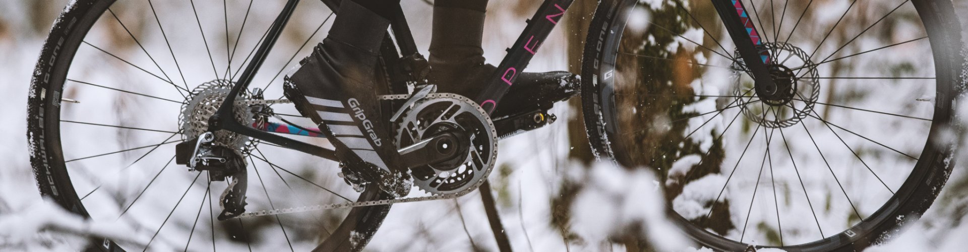 Detalle de pies pedaleando una bicicleta en un paisaje nevado.
