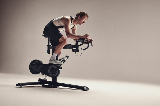 A man trains on a Wahoo smart bike in the white, seamless backdrop of a photo studio.