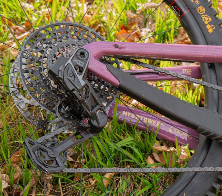En el triángulo trasero de una MTB púrpura tumbada está montado un grupo de transmisión SRAM AXS.