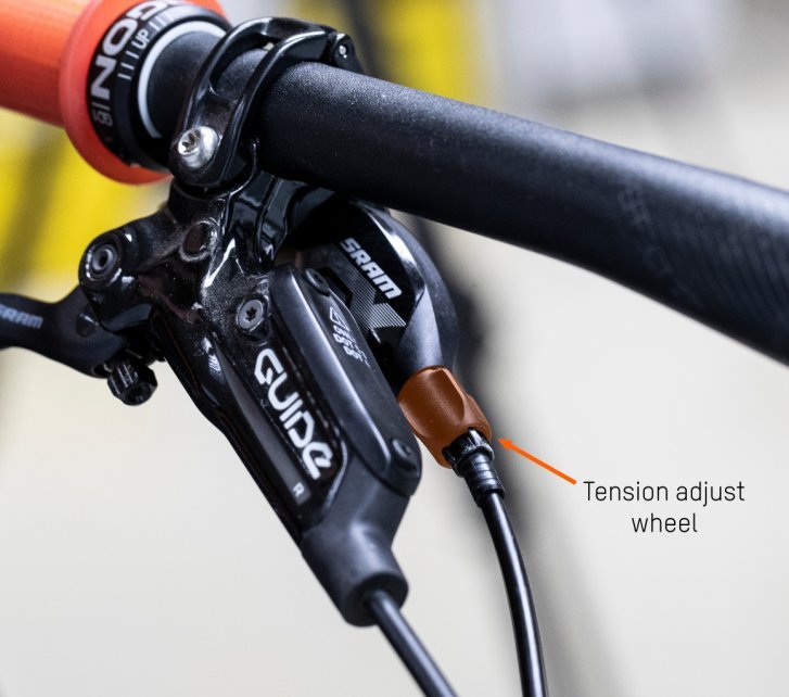 The tension adjust screw is visible. This is located directly on the handlebars at grip height on the MTB. An arrow points to the exact spot.