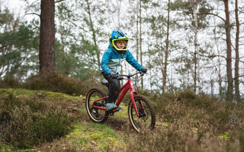 Ein Kind fährt mit dem SUPURB BO20 einen Trail im Wald