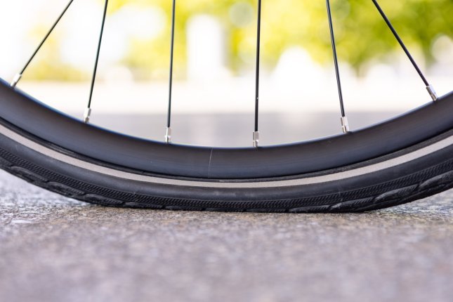 Close-up photo: A bicycle tyre with too little air is heavily compressed. The contact patch looks enormous.