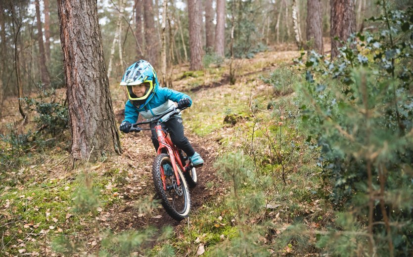 Ein Kind fährt mit dem SUPURB BO20 einen Trail im Wald