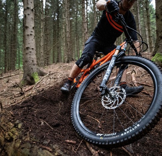 Christian fait un drift avec son VTT YETI sur un terrain boisé.