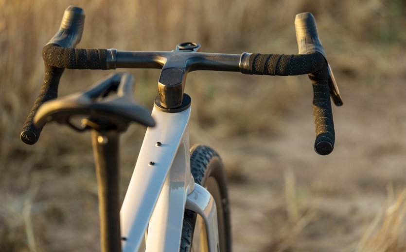 Cockpit of the OPEN WI.DE gravel bike with integrated handlebar and wide tires in dry grass.