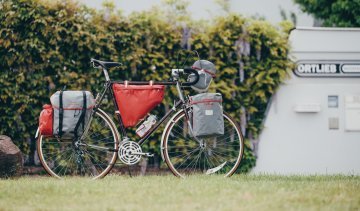 La photo montre un vélo de route en acier qui est équipé de diverses sacoches pour le bikepacking d'Ortlieb.