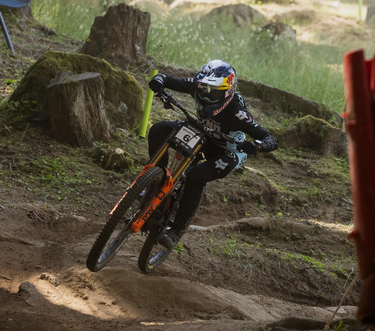 Downhill-Mountainbiker in FOX Racing Bekleidung nimmt eine Kurve auf der Waldstrecke