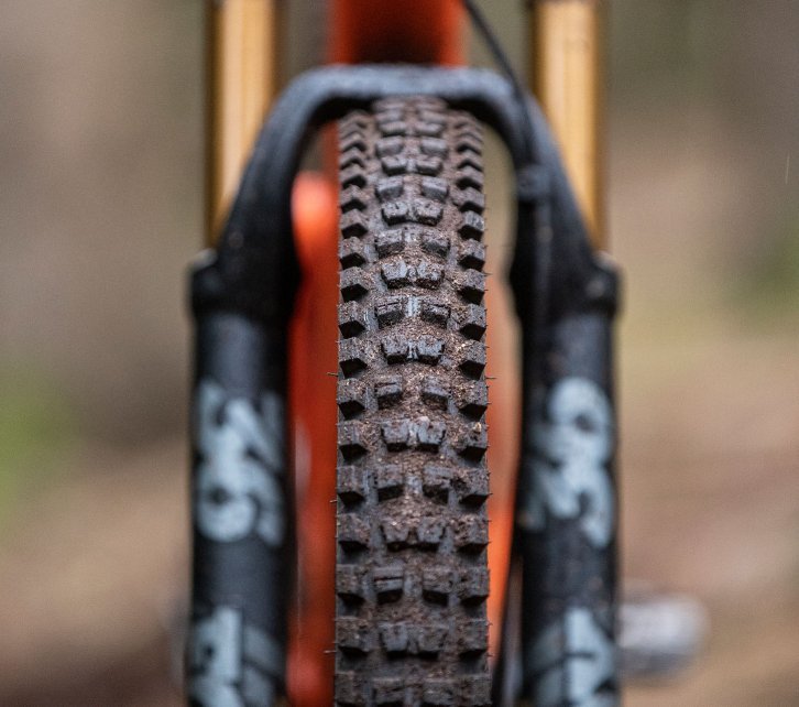 La photo montre le profil d'un pneu de VTT. Le cadrage montre le vélo de face, de sorte que toute la largeur du pneu est visible. 