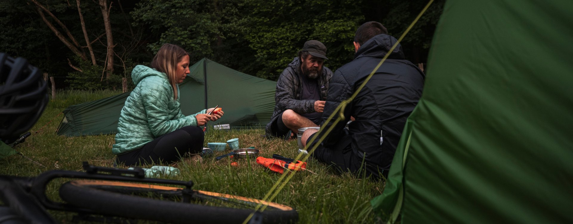 3 bc employees sitting in front of their tents preparing dinner.